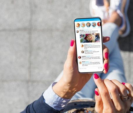 Person holding a cell phone displaying a social media feed.